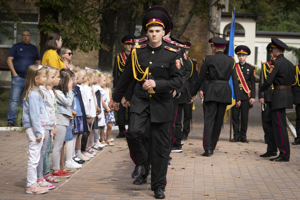 Young schoolgirls watch as cadets march during a rehearsal of a ceremony on the first day of school at a cadet lyceum in Kyiv, Ukraine, Thursday, Sept. 1, 2022. (AP Photo/Efrem Lukatsky)