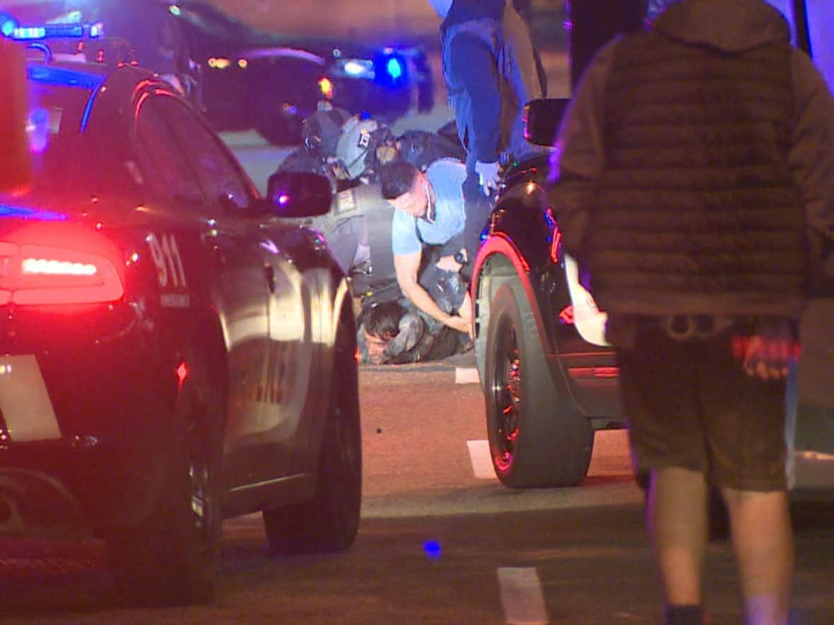 Vancouver police officers hold down a bank robbery suspect who allegedly barricaded himself inside a taxi for two hours on Thursday. (Shawn Foss/CBC - image credit)