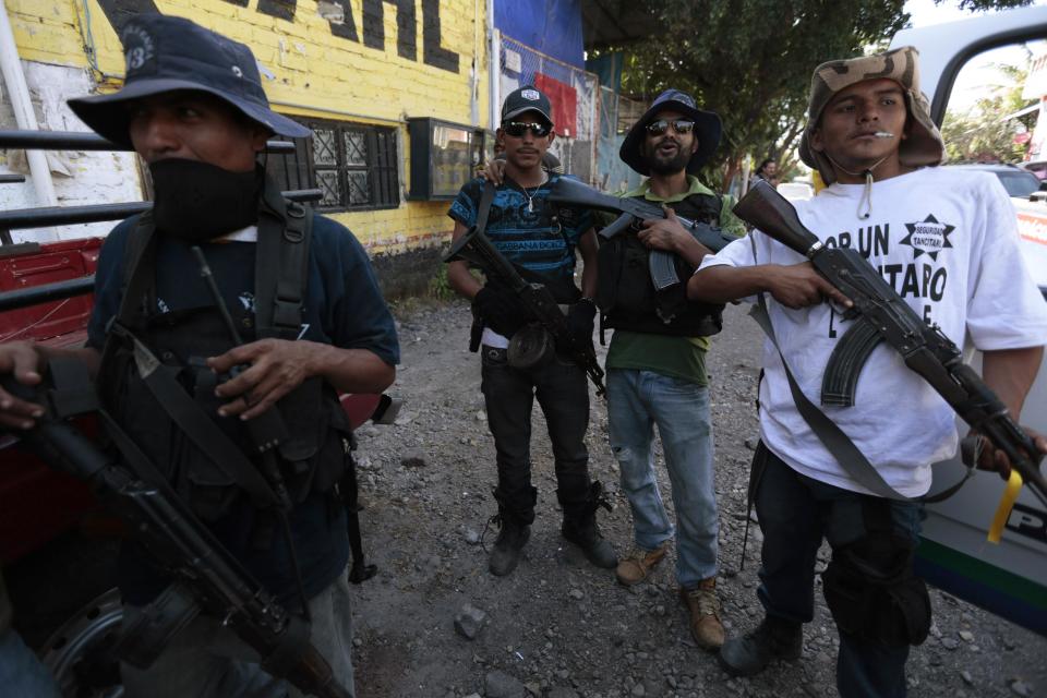 Members of community police, acting in this case as vigilantes, stand together after breaking into village of Paracuaro, and taking over, in Michoacan state