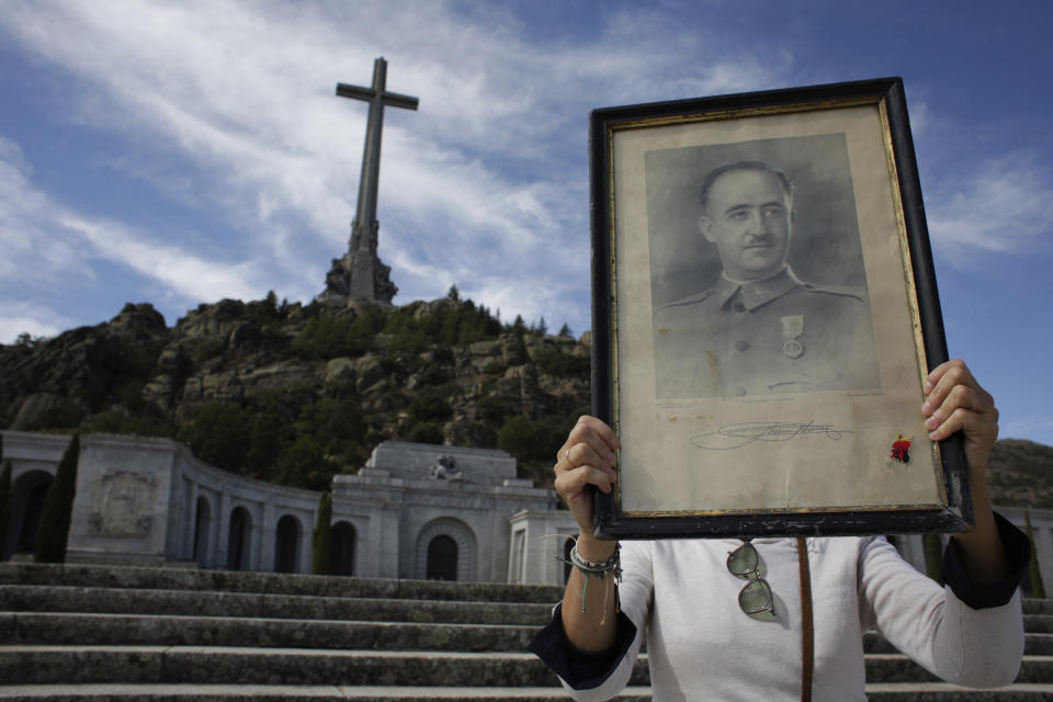 In this Friday, Oct. 4, 2019 photo, a visitors holds a portrait of former Spanish dictator Francisco Franco at the Valley of the Fallen mausoleum near El Escorial, outskirts of Madrid, Spain. After a tortuous judicial and public relations battle, Spain's Socialist government has announced that Gen. Francisco Franco's embalmed body will be relocated from a controversial shrine to a small public cemetery where the former dictator's remains will lie along his deceased wife. (AP Photo/Alfonso Ruiz)