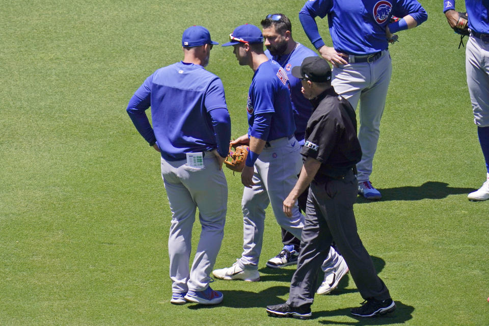 Chicago Cubs shortstop Nico Hoerner, center, walks with a trainer after injuring himself when he collided with umpire Dan Iassogna, foreground right, during the first inning of a baseball game against the San Diego Padres, Wednesday, May 11, 2022, in San Diego. (AP Photo/Gregory Bull)