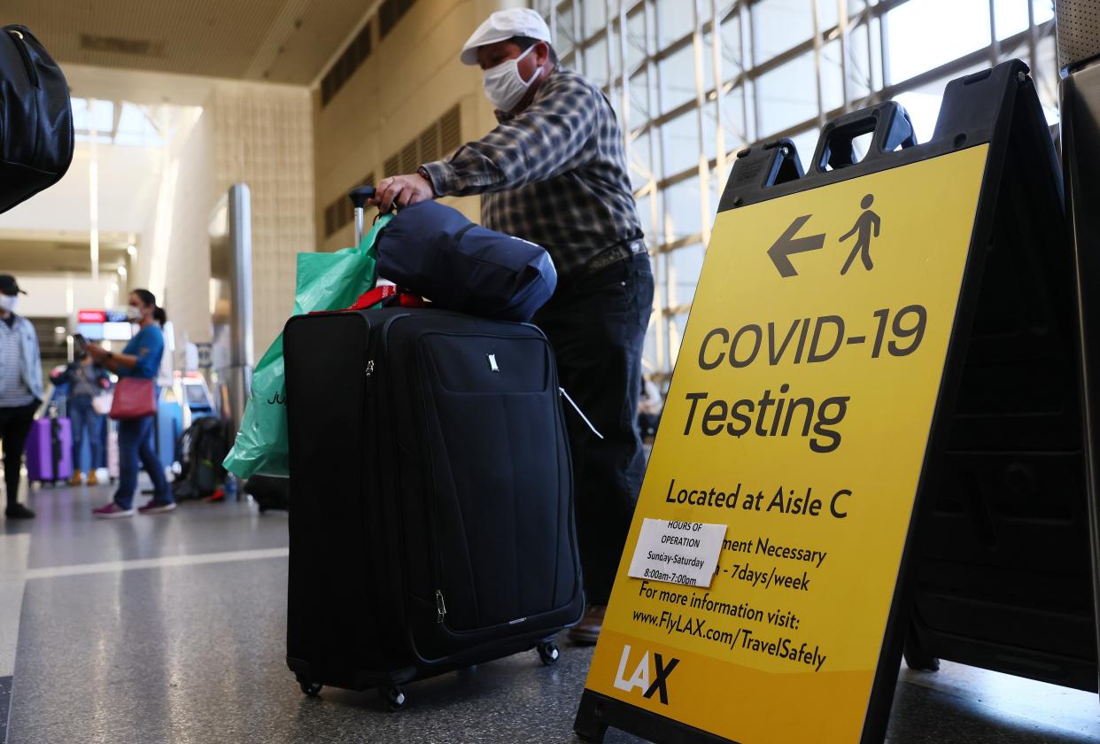 <p>People wait in line to check in near a sign pointing to a Covid-19 testing area in the Tom Bradley International Terminal at Los Angeles International Airport (LAX)</p> ((Getty Images))