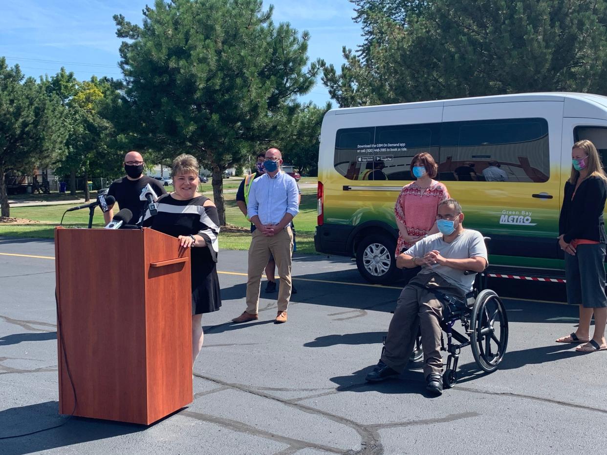Patricia Kiewiz, transit director for Green Bay Metro, makes an announcement with one of the leased "microtransit" buses in the background. G.B. Metro is expanding microtransit service as a way to increase the hours that bus service is available to riders. (File photo)