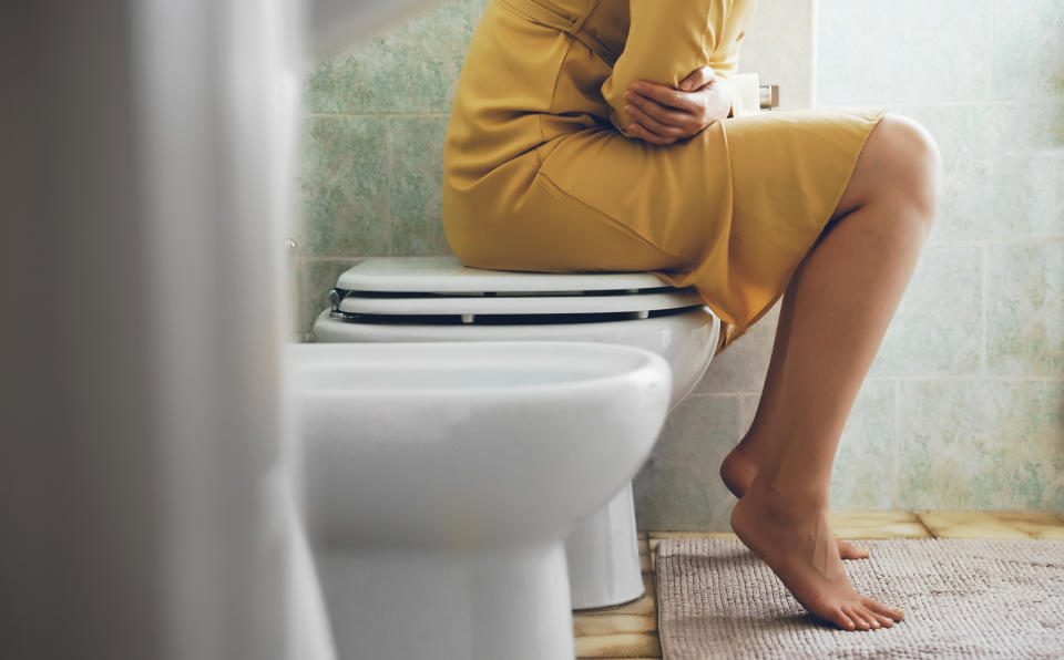 Unrecognizable woman on the toilet with stomach pain.