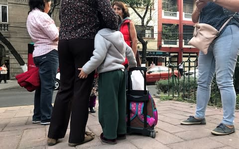 People stand on the street after hearing an earthquake alarm in Mexico City - Credit: Reuters