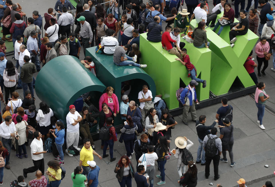 People climb across giant letters representing the city's Spanish initials, as supporters of Mexican President Andres Manuel Lopez Obrador gather for a rally on the one-year anniversary of his election, in the Zocalo, Mexico City's main square, Monday, July 1, 2019.(AP Photo/Rebecca Blackwell)