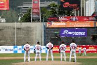 Players of Tiburones de La Guaira team, sing the national anthem before a game at University Stadium in Caracas