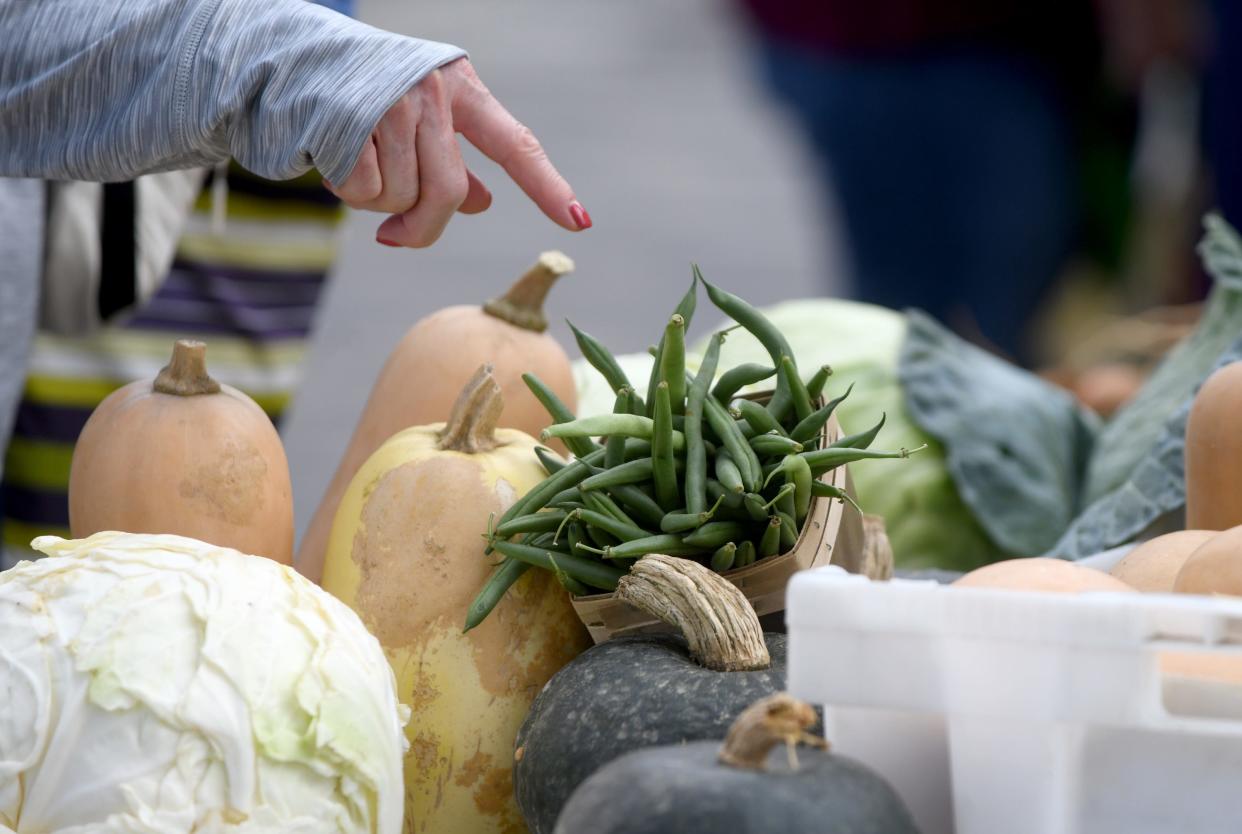 A customer selects a variety of items from May's Produce of Randolph at the Canton Farmers Market in downtown Canton.