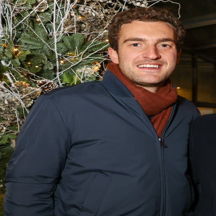 closeup of him outside wearing a jacket and holding a beer