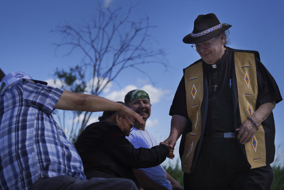 The Rev. Gary Laboucane, left, shakes hands with Mary and Ken Kootenayoo, during a press conference at the Lac Ste. Anne pilgrimage site in Alberta on Wednesday, July 20, 2022. Pope Francis is scheduled to make a pilgrimage to the sacred lake during his visit to the Canadian province. (AP Photo/Jessie Wardarski)