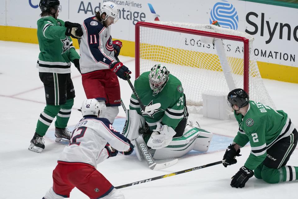 Dallas Stars goaltender Anton Khudobin (35) blocks a shot from Columbus Blue Jackets center Alexandre Texier (42) as defensemen Miro Heiskanen, left, and Jamie Oleksiak (2) and Blue Jackets' Kevin Stenlund (11) look for a rebound during the second period of an NHL hockey game in Dallas, Thursday, March 4, 2021. (AP Photo/Tony Gutierrez)