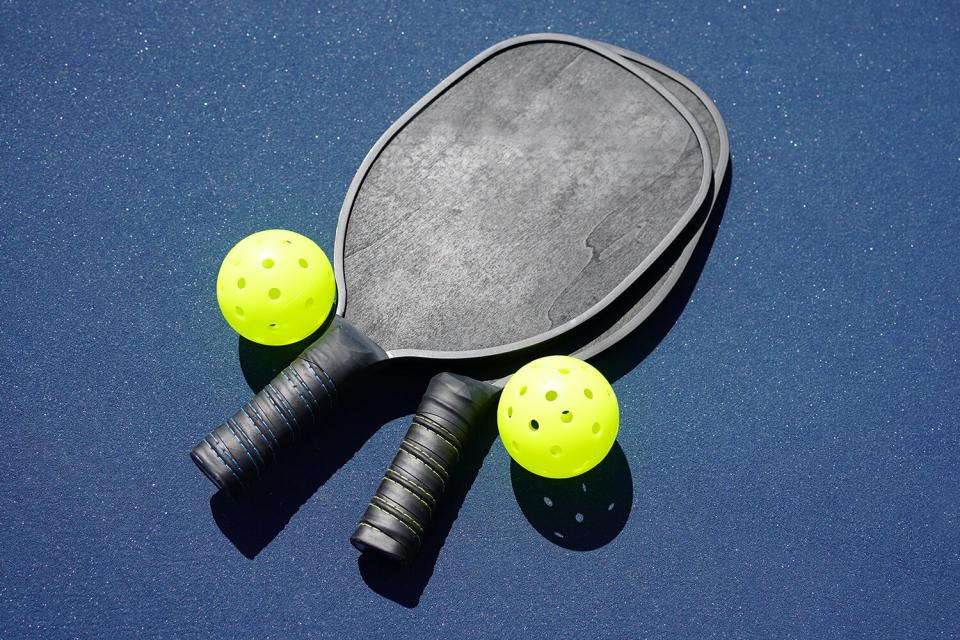 Two pickleball paddles and two pickleballs on court