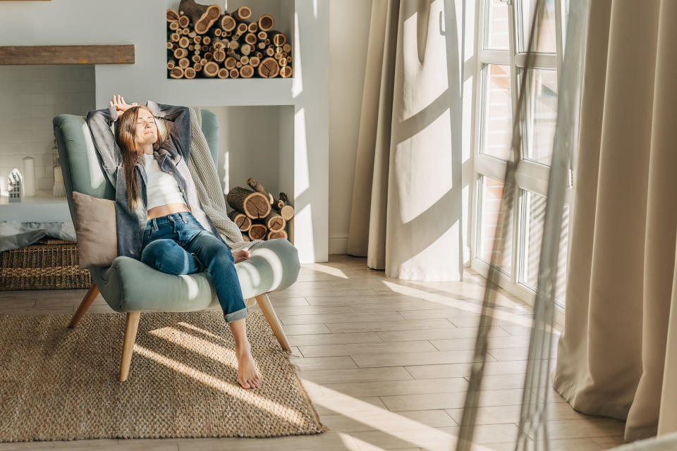 a woman sitting in a comfortable chair, bathed in sunlight