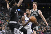 Sacramento Kings' Harrison Barnes, center, drives between San Antonio Spurs' Stanley Johnson, left, and Jakob Poeltl during the first half of an NBA basketball game, Wednesday, Feb. 1, 2023, in San Antonio. (AP Photo/Darren Abate)