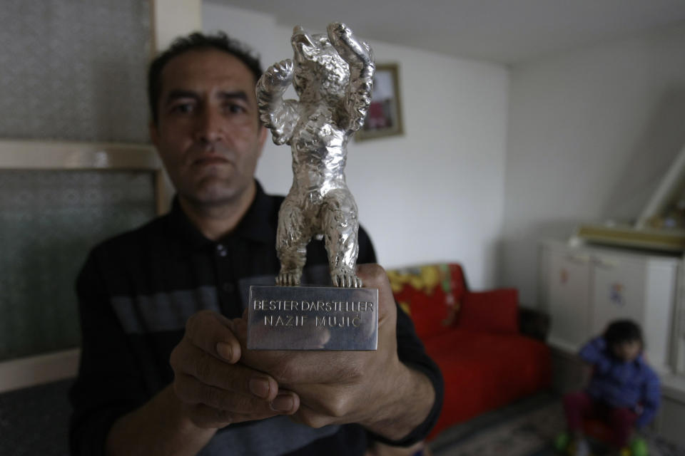 Nazif Mujic, the Gypsy scrap metal collector shows his award - the Silver Bear for best actor of the 63rd Berlin Film Festival at his home in the village of Poljice, 150 kms northeast of Sarajevo, on Wednesday, April 10, 2013. People in the Gypsy village of Poljice say they will never forget the night they almost fell off their chairs two months ago. Did they really hear the elegant woman on TV correctly? Could she really be talking about their neighbor, the toothless man who passed his days selling scrap metal and lived in the shack down the road? The camera switched to a frightened-looking Najif Mujic. Yes it was him. THEIR Nazif _ who had just left Matt Damon and Jude Law in the dust to win the best actor award at the Berlin Film Festival. (AP Photo/Amel Emric)