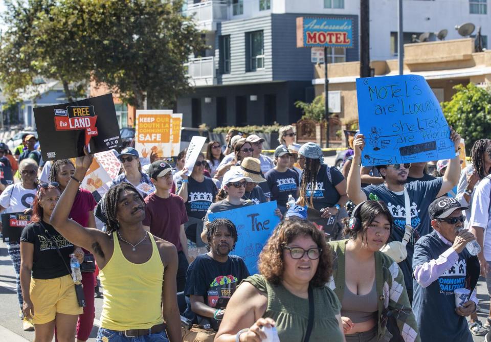 People march, hold signs to protest motels on Figueroa Street.