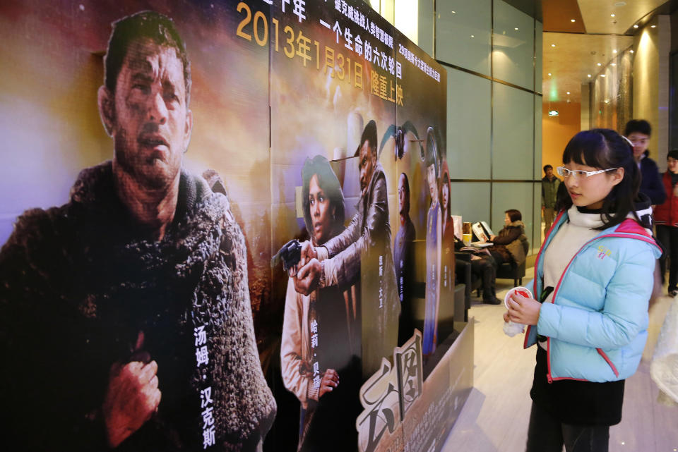 In this photo taken Wednesday, Feb. 13, 2013, a woman looks at an advertisement for the U.S. film "Cloud Atlas" at a movie theater, in Shanghai, China. Tens of millions of film fanatics are entering theaters around Asia during the long Lunar New Year holiday, but Hollywood can’t count on them to boost the box office for its mostly serious Oscar nominees. Even with the Academy Awards buzz at a peak barely two weeks before the ceremony, patrons are opting for lighter fare. (AP Photo)