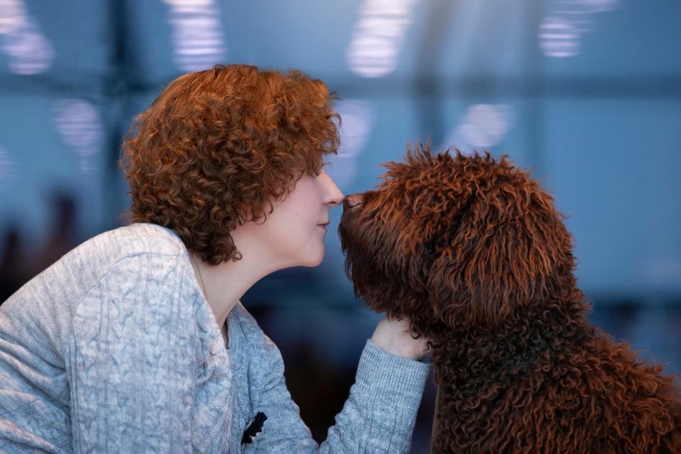 A woman with red curly hair and a dog with red curly hair.