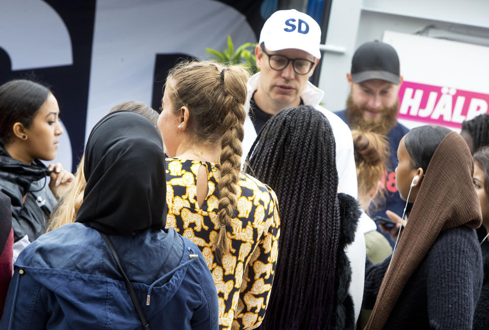In this Aug. 31, 2018 photo young women listen to a party member of the right wing Sweden Democrats In Stockholm, Sweden. (AP Photo/Michael Probst)