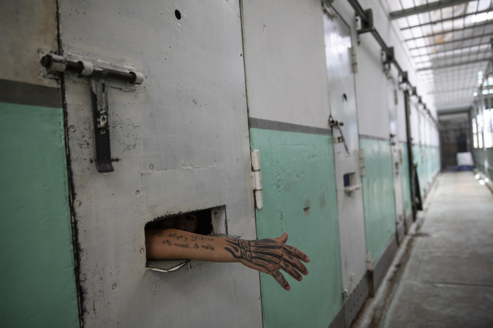 Jeremias Echague shows his tattoo from inside his cell within the evangelical cellblock he joined at the Correctional Institute Model U.1., Dr. Cesar R Tabares, known as Penal Unit 1 in Coronda, Santa Fe province, Argentina, where the 19-year-old waits for his final sentencing for homicide, Friday, Nov. 19, 2021. Many here began peddling drugs as teenagers and got stuck in a spiral of violence that led some to their graves and others to overcrowded prisons divided between two forces: drug lords and preachers. (AP Photo/Rodrigo Abd)