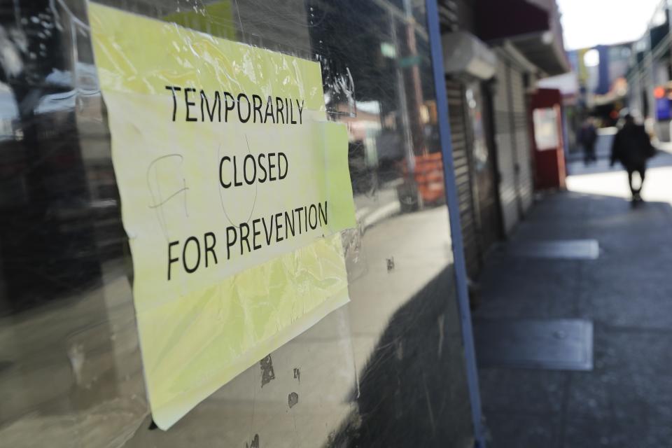 Pedestrians pass closed stores on Roosevelt Avenue Saturday, April 4, 2020, in the Queens borough of New York. The new coronavirus causes mild or moderate symptoms for most people, but for some, especially older adults and people with existing health problems, it can cause more severe illness or death. (AP Photo/Frank Franklin II)