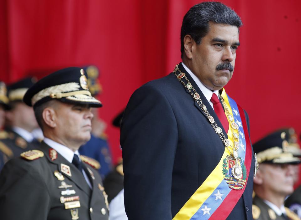 FILE - In this May 24, 2018 file photo, Venezuela's President Nicolas Maduro watches a military parade, alongside his Defense Minister Vladimir Padrino Lopez, behind, at Fort Tiuna in Caracas, Venezuela. State television in Venezuela showed President Maduro abruptly cutting short a speech on Saturday, Aug. 4, causing hundreds of soldiers present to break ranks and scatter.(AP Photo/Ariana Cubillos, File)