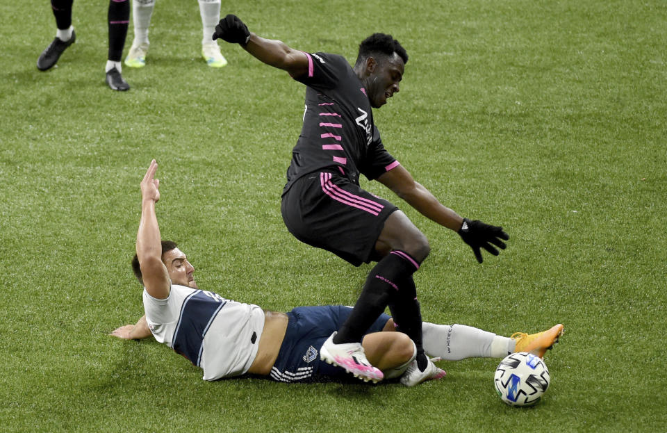 Vancouver Whitecaps forward Lucas Cavallini, left, pokes the ball away as he slides in on Seattle Sounders defender Yeimar Gomez during the second half of an MLS soccer match in Portland, Ore., Tuesday, Oct. 27, 2020. Seattle won 2-0. (AP Photo/Steve Dykes)