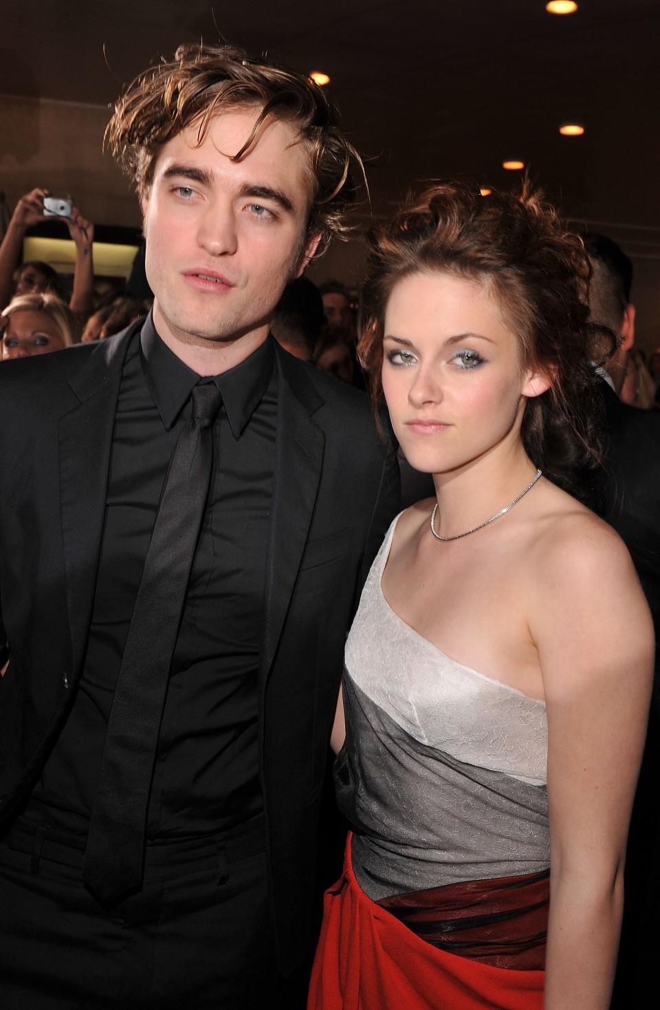 Robert Pattinson in a black suit and Kristen Stweart in a light grey dress
