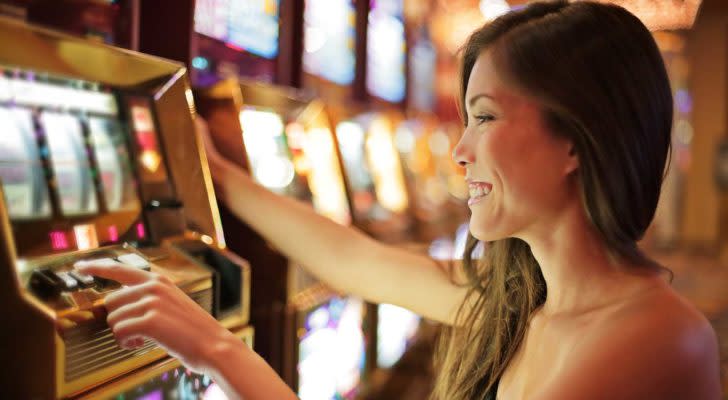 a woman smiling while using a slot machine in a casino. representing gambling stocks