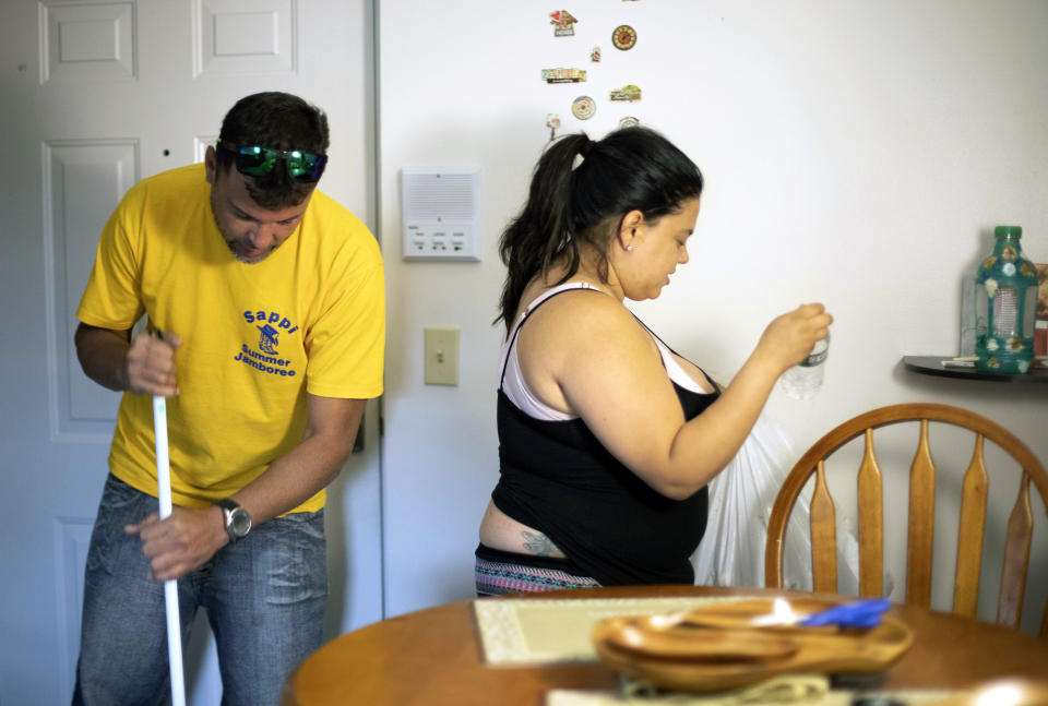 In this Aug. 2, 2019 photo, Ashlyn Gonzales, right, and her longtime partner Emanuel Rivera clean their condo after work in Portland, Conn. In the months after Hurricane Maria destroyed her home in Puerto Rico, Gonzales moved to Connecticut, where federal and state aid helped her and Rivera avoid homelessness. But aid at both levels has just about dried up, leaving Gonzales and many like her wondering what they are going to do next. (AP Photo/Chris Ehrmann)