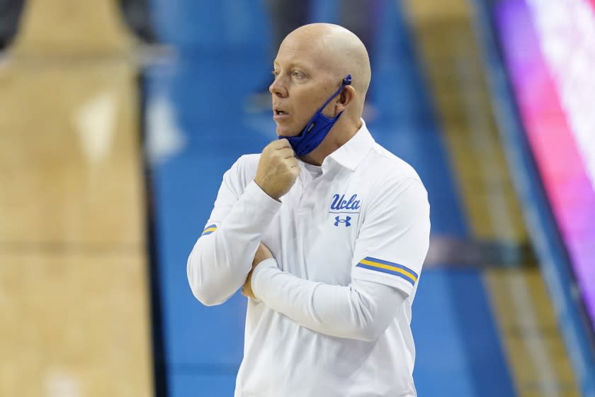 UCLA coach Mick Cronin adjusts his mask on the sideline during the first half of the team's.