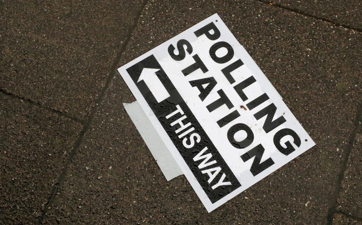 A polling station signpost lies on the pavement