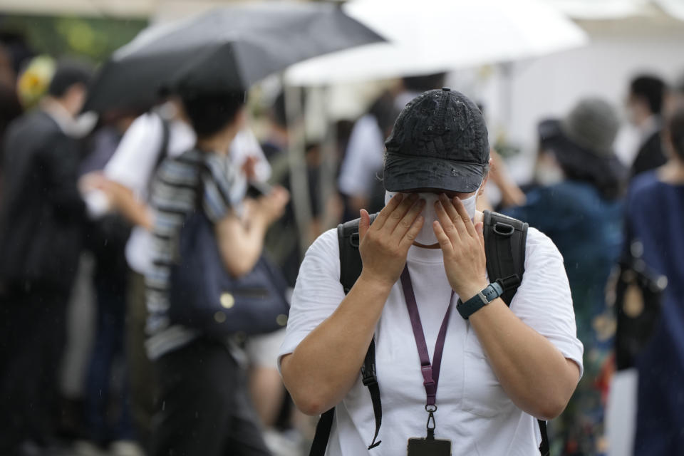 One of people who offer flowers and prayers for former Prime Minister Shinzo Abe, cries at Zojoji temple prior to his funeral wake Tuesday, July 12, 2022, in Tokyo. Abe was assassinated Friday while campaigning in Nara, western Japan. (AP Photo/Eugene Hoshiko)