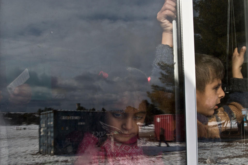 A Syrian girl looks out a shelter window at the Ritsona refugee camp in Greece