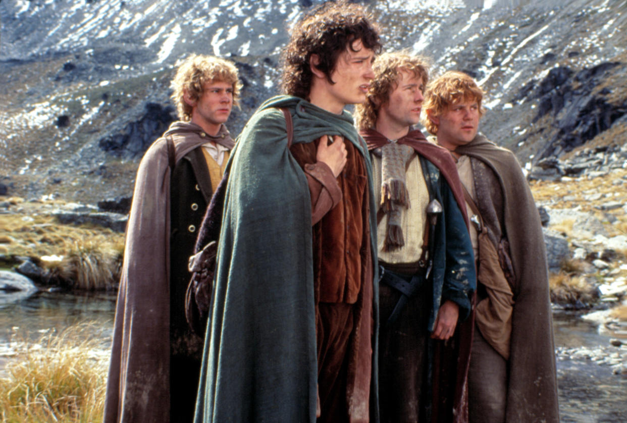 Dominic Monaghan, Elijah Wood, Billy Boyd and Sean Astin dressed as hobbits in a film scene.