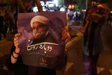 A supporter of Iranian president Hassan Rouhani holds his poster as she celebrates his victory in the presidential election, in Tehran, Iran, May 20, 2017. TIMA via REUTERS
