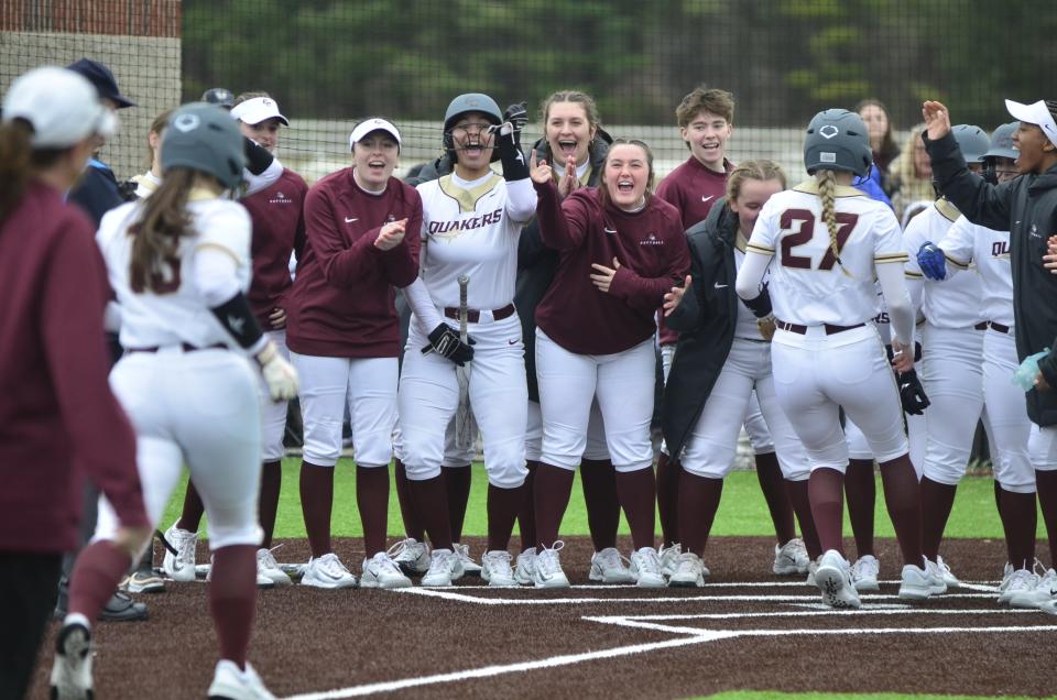 Earlham players surround home plate to celebrate Emmerie Stump's three-run home run in the first game of a doubleheader against Olivet, Saturday, March 2, 2024. Earlham won both games for its first wins in 31 years.