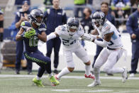 Seattle Seahawks' Tyler Lockett, left, breaks from the grasp of Tennessee Titans cornerback Elijah Molden (24) to run for a touchdown after a reception as strong safety Bradley McDougald (30) looks on during the first half of an NFL football game, Sunday, Sept. 19, 2021, in Seattle. (AP Photo/John Froschauer)