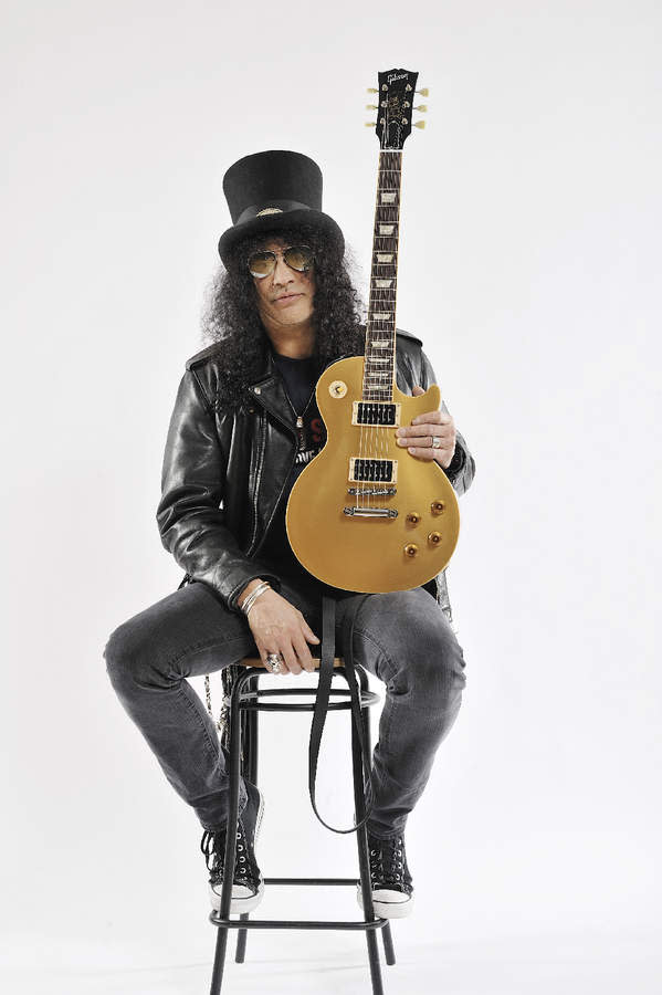 Slash sitting on a stool holding a Les Paul guitar