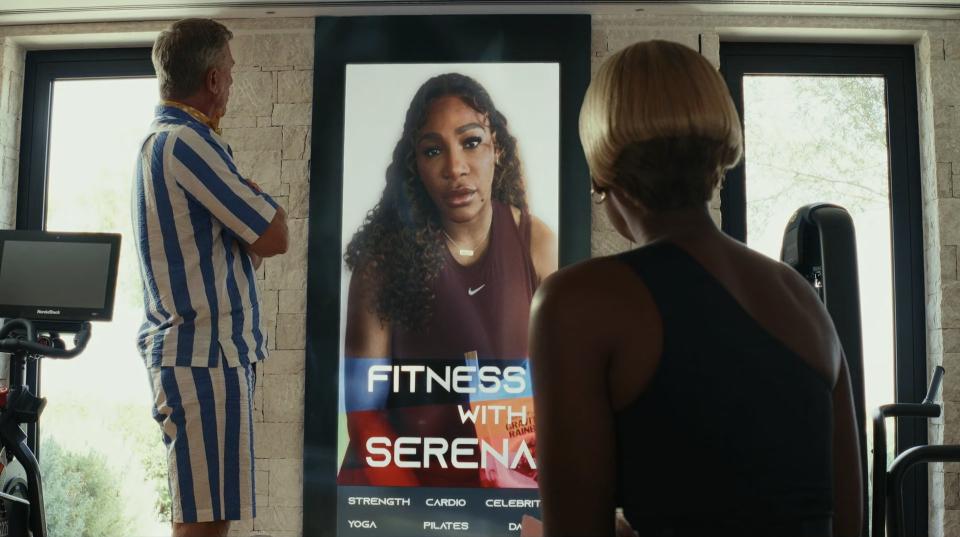 Serena Williams speaks on a screen while Janelle Monáe and Daniel Craig look at her