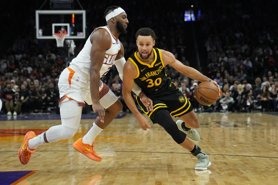 Golden State Warriors guard Stephen Curry (30) drives on Phoenix Suns forward Josh Okogie during the first half of an NBA basketball game, Wednesday, Nov. 22, 2023, in Phoenix. (AP Photo/Matt York)