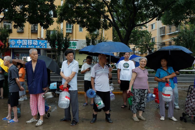 People line up for drinking water in a neighbourhood where Typhoon Doksuri caused flooding, in Beijing