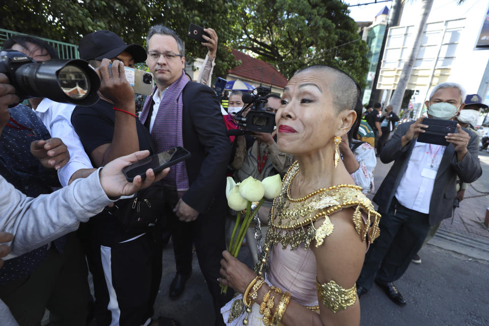 Theary Seng, right, a Cambodian-American human rights lawyer, dressed in a traditional Khmer Apsara dance costume, speak with media as she arrives to continue her trial in the municipal court in Phnom Penh, Cambodia, Tuesday, Dec. 7, 2021. Seng and over 40 other defendants charged with treason for taking part in nonviolent political activities were summoned back to court Tuesday to continue their trial that had been suspended since November 2020 due to the coronavirus. (AP Photo/Heng Sinith)