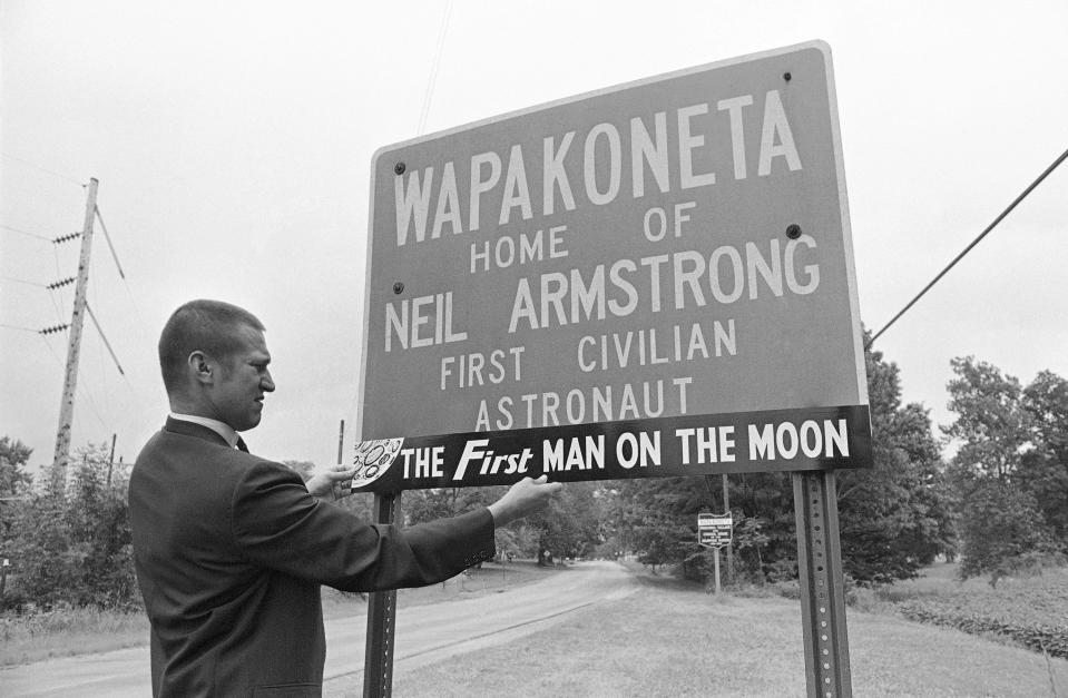 In this July 21, 1969 file photo, Charles Brading, a druggist and personal friend of astronaut Neil Armstrong, checks the size and placing of a temporary sign addition proclaiming their local hero in Wapakoneta, Ohio. in 1969.