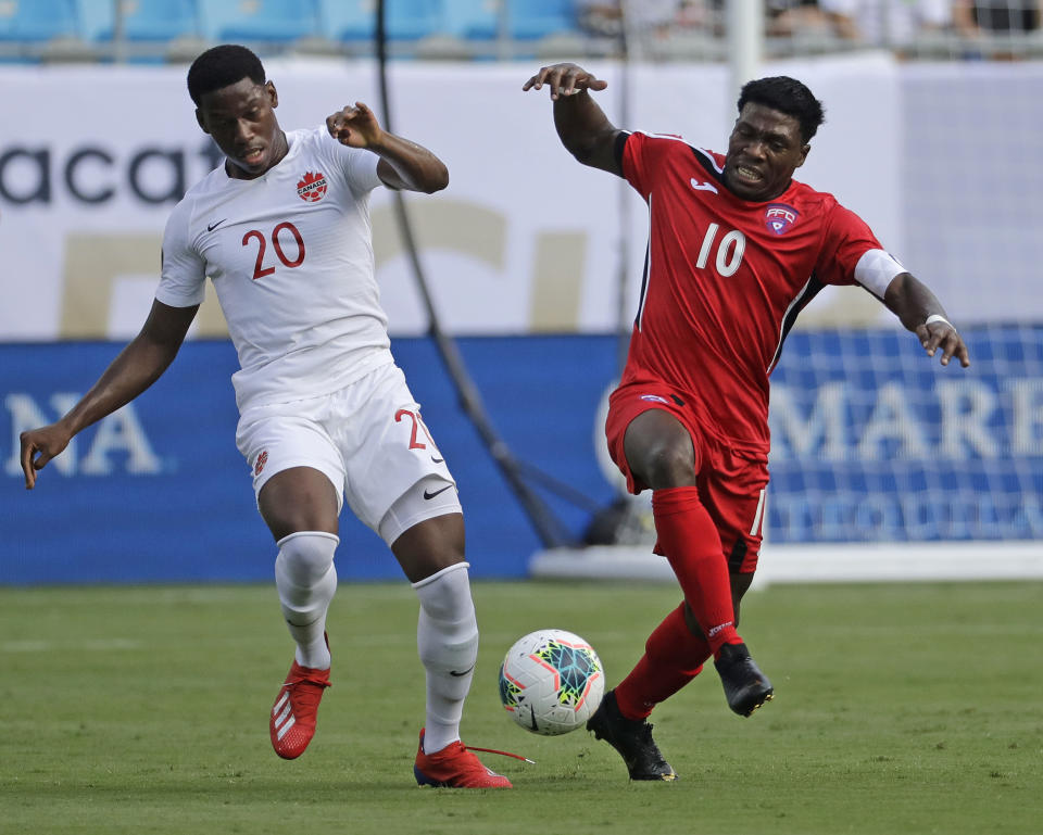 Canada's Jonathan David (20) battles Cuba's Aricheell Hernandez (10) during the first half of their CONCACAF Golf Cup soccer match in Charlotte, N.C., Sunday, June 23, 2019. (AP Photo/Chuck Burton)