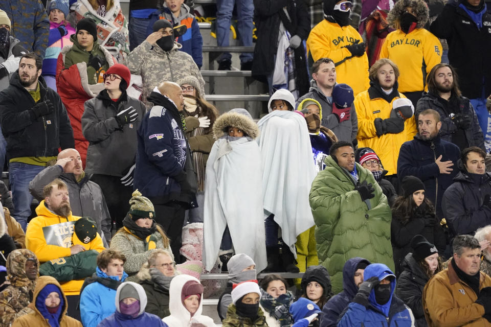 Bundled-up fans stand during the national anthem before the Armed Forces Bowl NCAA college football game between Baylor and Air Force in Fort Worth, Texas, Thursday, Dec. 22, 2022. (AP Photo/LM Otero)