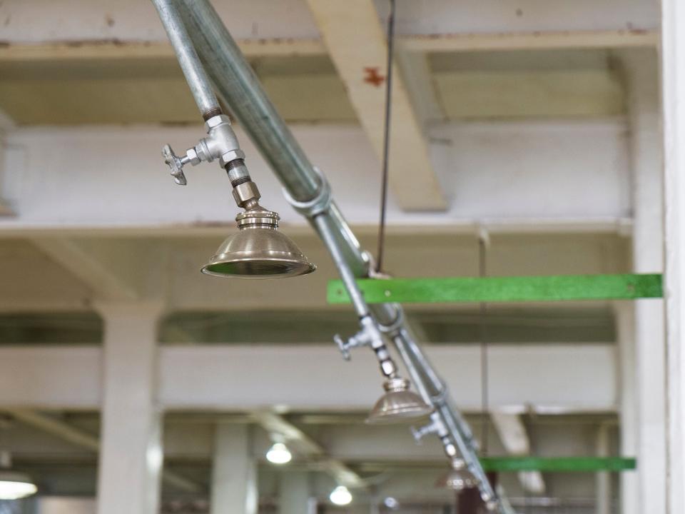 Shower from steel tube hanging from ceiling for prisoner in shower area of Alcatraz prison.