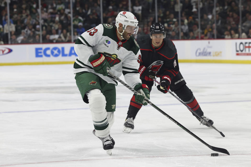 Minnesota Wild defenseman Alex Goligoski (33) handles the puck in front of Carolina Hurricanes center Jack Drury during the first period of an NHL hockey game Saturday, Nov. 19, 2022, in St. Paul, Minn. (AP Photo/Stacy Bengs)