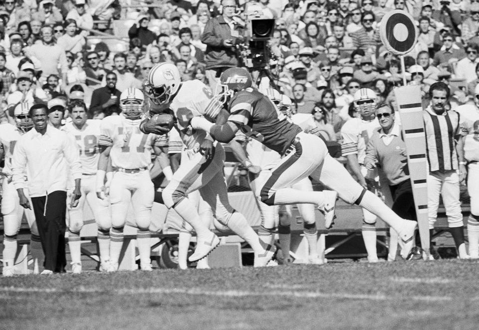 Miami Dolphins wide receiver Nat Moore, left, eludes the New York Jets Ken Schroy on his way to a first quarter touchdown at Shea Stadium in New York, Oct. 16, 1983. It was the first score of the game. (AP Photo/Bill Kostroun)