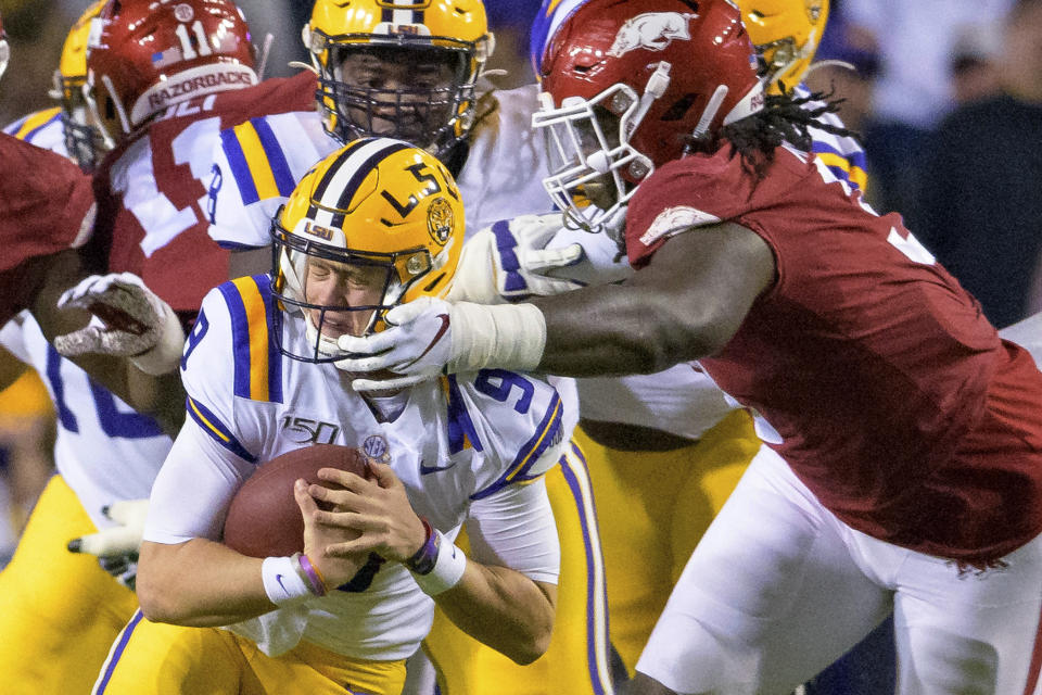 LSU quarterback Joe Burrow (9) tries to get away from Arkansas defensive lineman McTelvin Agim (3) during the first half of an NCAA college football game in Baton Rouge, La., Saturday, Nov. 23, 2019. (AP Photo/Matthew Hinton)